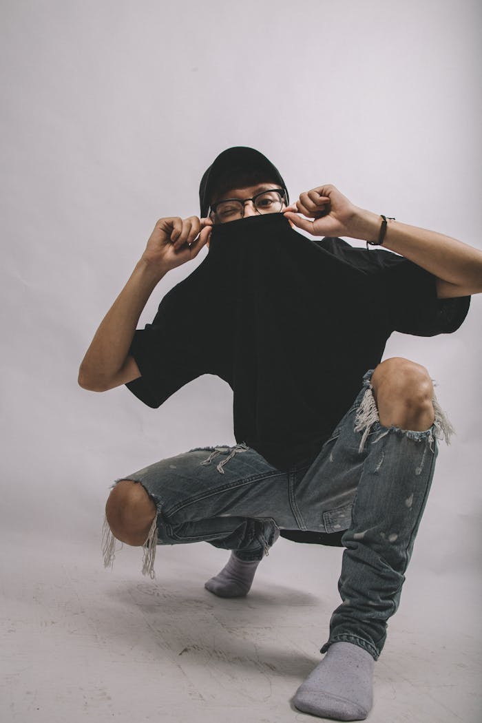 Man in Black Crew-neck Shirt and Blue Distressed Jeans Wearing Eyeglasses